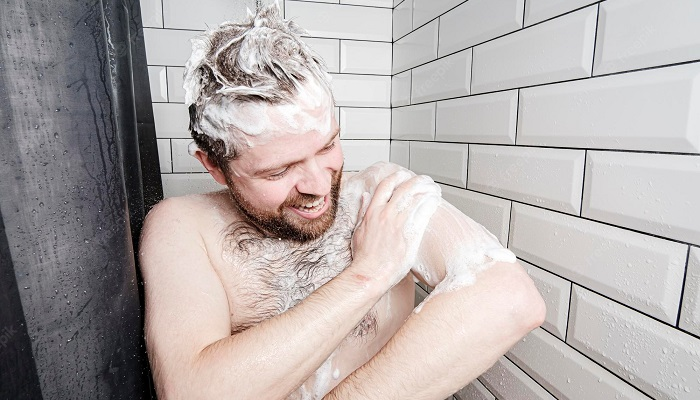 Hombre gracioso enjabonándose en la ducha